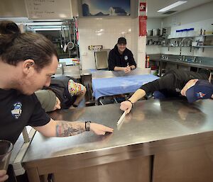 A couple of expeditioners inspecting the surface of a steel table top in the kitchen