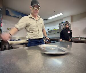 An expeditioner releases the now spinning Bain-marie lid on a kitchen top bench