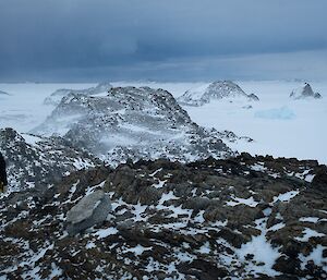 A person stands amid rocky and snowy peaks