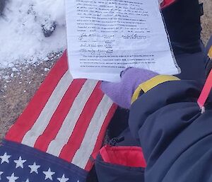 hands covered by purple gloves hold a letter over the American flag.