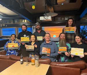 A group of people pose with their artwork in a lounge area