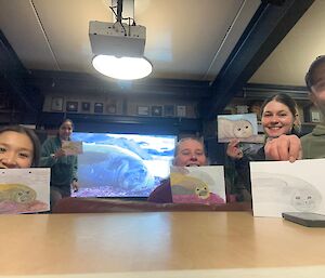 A group of people pose with their artwork in a lounge area