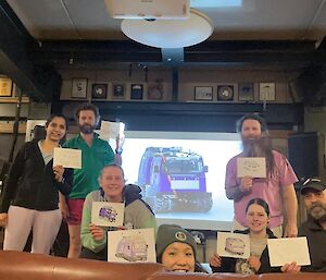 A group of people pose with their artwork in a lounge area