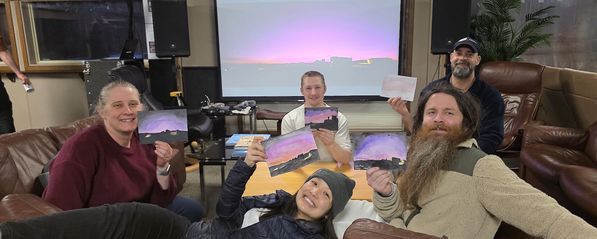 A group of people pose with their artwork in a lounge area