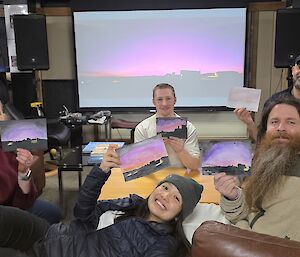 A group of people pose with their artwork in a lounge area