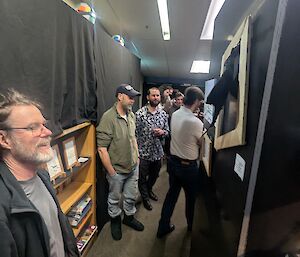 A group of expeditioners move through the gallery admiring the art