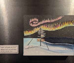 A canvas with a starry night image painted onto it, with aurora australis embroidered in the sky