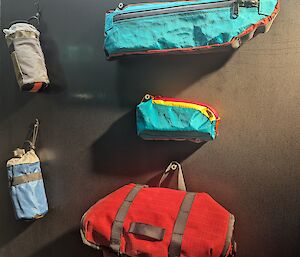 Various bags and drink bottle holders designed to fit on a bike are hangin gon a black wall