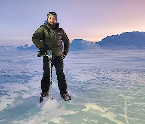 A man holding a drill on the ice