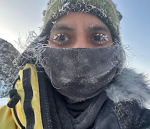 A woman with ice on her eye lashes and beanie in a snowy landscape