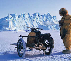 a historic picture of an expeditioner riding a motorcycle on the sea ice - customised with an extra rear wheel/sidecar platform