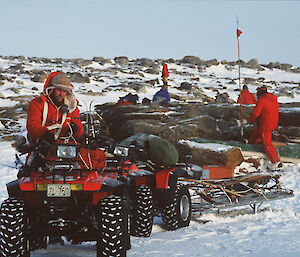 a historical picture of couple of quad bikes with rider, towing a sled