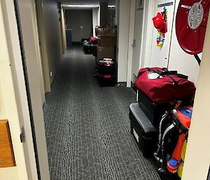 A long corrido with rooms on the right-hand side hads bags, boxes and tubs stacked outside a number of rooms