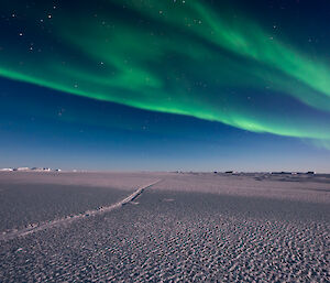 sea ice photo with tidal crack, while green aurora is above