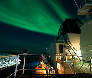 A photo of a green aurora overhead while on the upper decks of the Nuyina