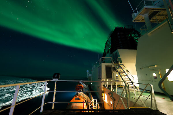 A photo of a green aurora overhead while on the upper decks of the Nuyina