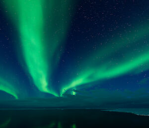 A photo of strands of green aurora overhead while on the back deck of the Nuyina