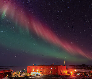 A red purple and green aurora over the station's Red Shed