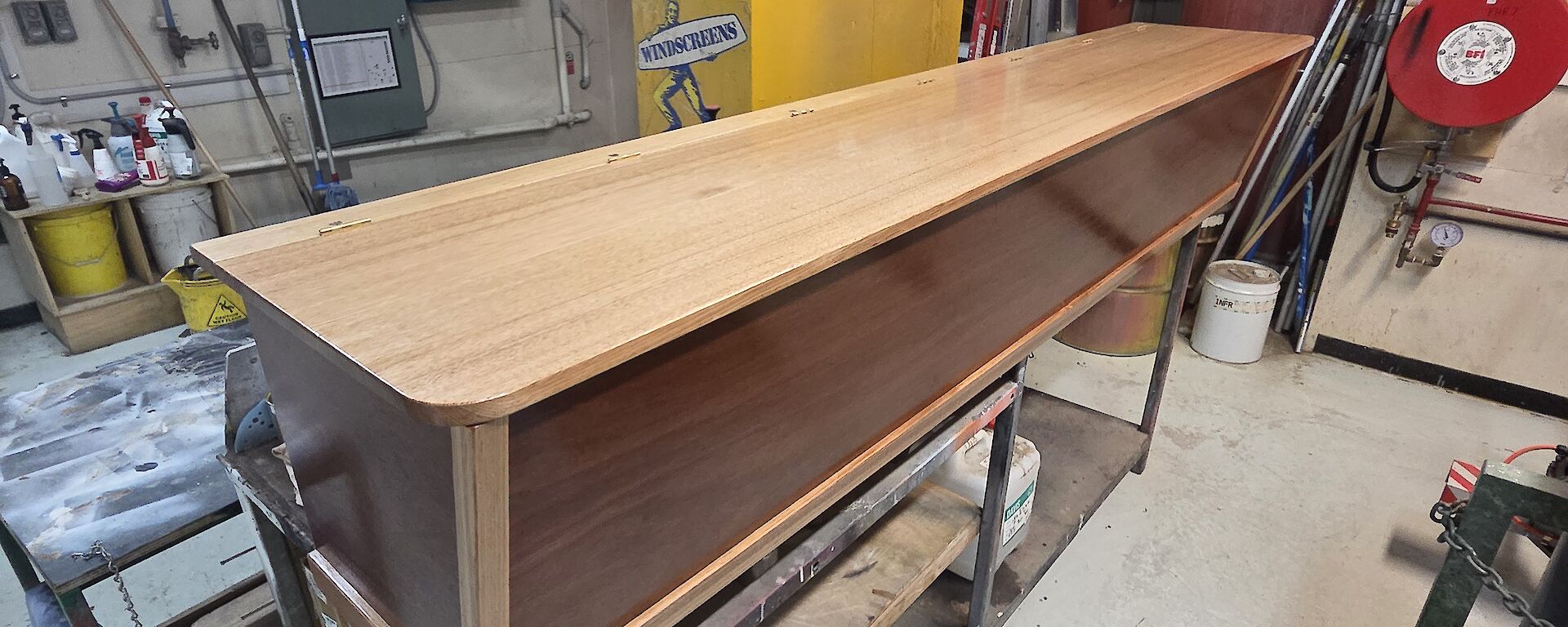 A polished wooden box sits on a bench in a workshop