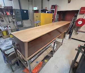 A polished wooden box sits on a bench in a workshop