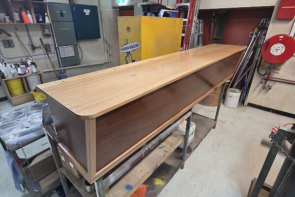 A polished wooden box sits on a bench in a workshop