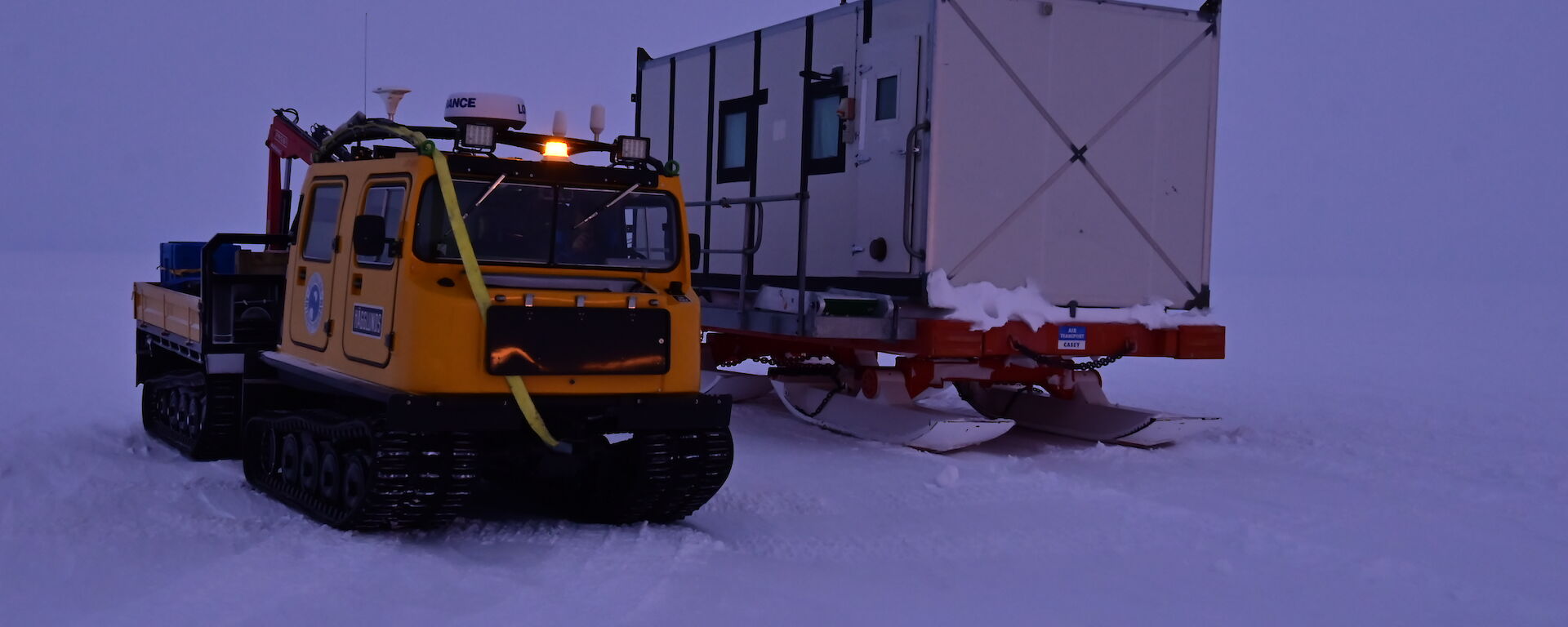 A yellow hagg on a white surface with a living container next to it