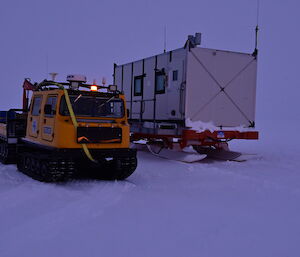 A yellow hagg on a white surface with a living container next to it
