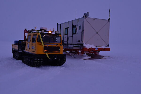 A yellow hagg on a white surface with a living container next to it