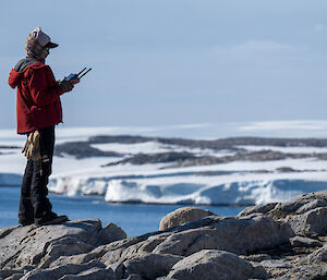 A person stands on a hill with ice in the background