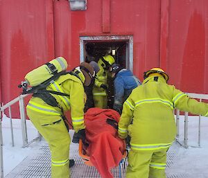 Emergency response expeditioners carry a person into a red building