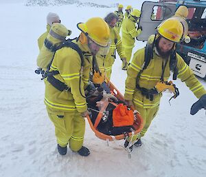 Emergency response expeditioners carry a person across the snow