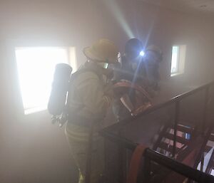 Emergency response expeditioners in a smoke-filled building. A head torch shines through the smoke.
