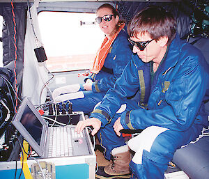 Expeditioners set up aerial survey equipment in a helicopter