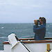 An expeditioner looks through binoculars for seabirds, from the vessel ‘Polar Bird'