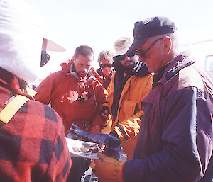 Scientists and field training officers discuss deployment of personnel and equipment with the helicopter pilot