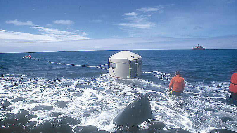A tank hut is towed through the surf by rubber boat to Aurora Australis