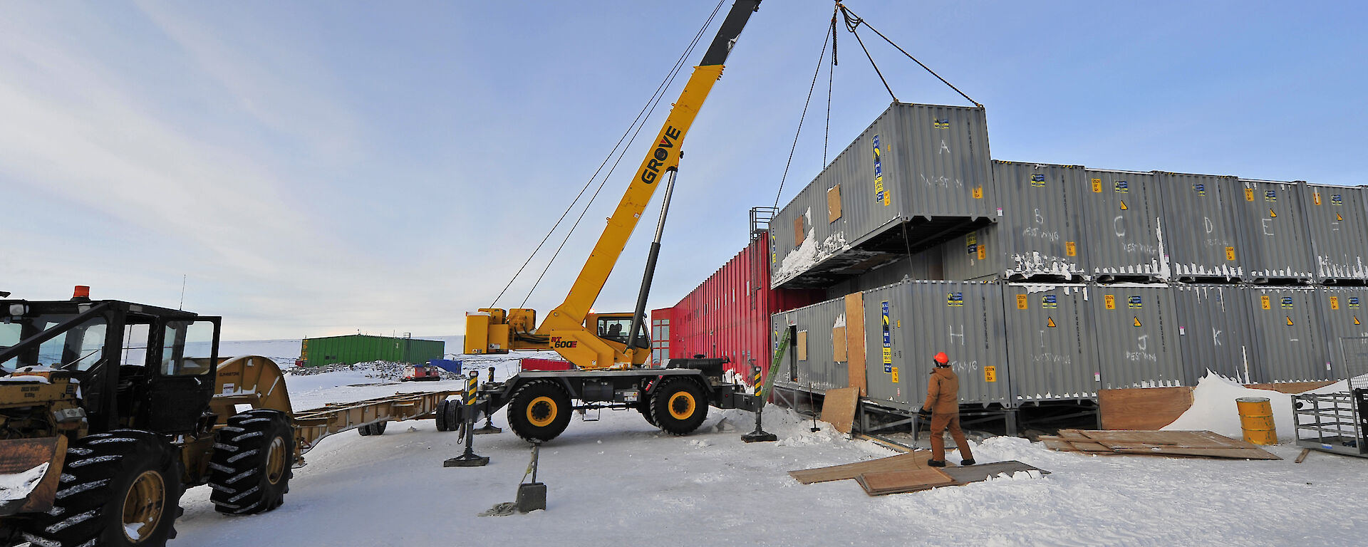 A tall crane moves a shipping container from a stack of them.