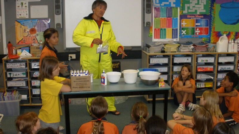 Scientist in a freezer suit demonstrating to school students how to make glacier goo