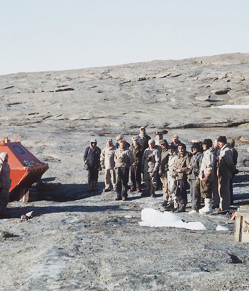 Phil Law stands at the foot of the flagpole, raised on 13 February 1954 at the establishment of Mawson station