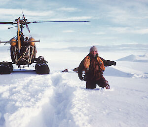 Phil Law in snow in Oates Land, with helicopter landed in the background.