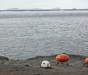 One apple hut and two ‘googie’ huts on Béchervaise Island with icebergs in the distance