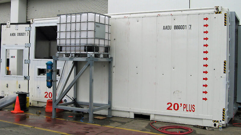 External view of the aquarium in a shipping container, with a separate seawater tank on a stand beside it.