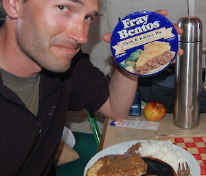 Phil with a cooked Fray Bentos pie and a picture of what it should look like