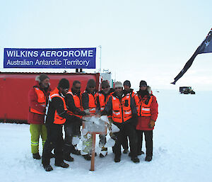 Matt, second from left, smashes ice from a plaque during the official opening of Wilkins Runway in January 2008.