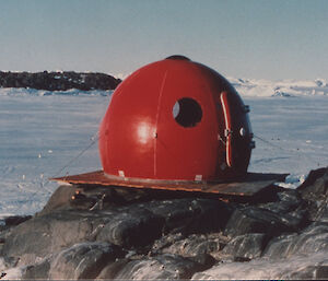 Igloo sited on a rocky area, with ice in the background