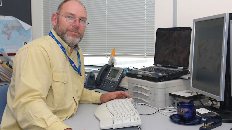 Man seated at desk in office with computer equipment