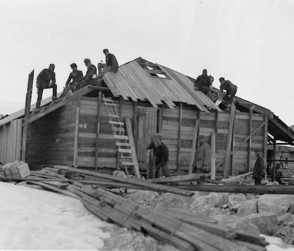 Mawson’s huts construction with workers on the roof and around the hut