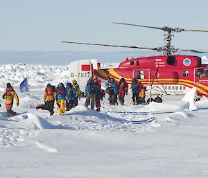 MV Akademik Shokalskiy passengers walk across sea ice from the Chinese helicopter to the Aurora Australis