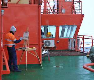 John Kelly painting on the deck of the Aurora Australis