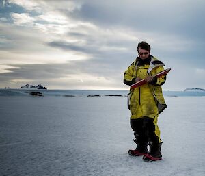John sketches on the sea ice at Mawson, with Mount Henderson in the background